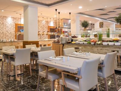 Modernes Hotelrestaurant mit gedeckten Tischen und einem Buffetbereich im Hintergrund