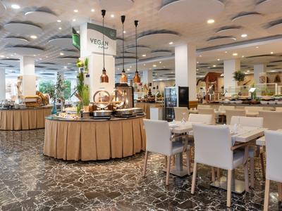 Großer, heller Speisesaal mit runden Buffets, weißen Stühlen und moderner Deckenbeleuchtung.