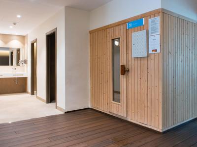 Hotelflur mit Sauna aus Holz und angrenzendem Badezimmer mit Waschbecken.