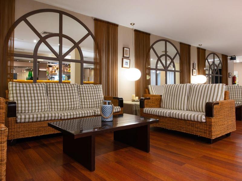 Gemütliche Lounge mit Rattansofas, karierten Polstern und Holzböden in einem Hotel.