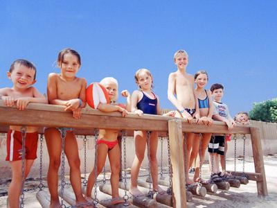 Niños alineados en una barandilla de madera en un día soleado de verano