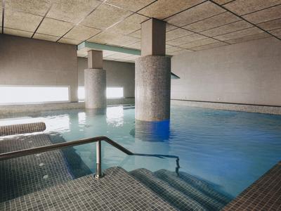 Piscina interior moderna con columnas de soporte y escaleras en un hotel.