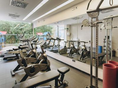 Sala fitness con attrezzature e parete a specchio in un hotel.
