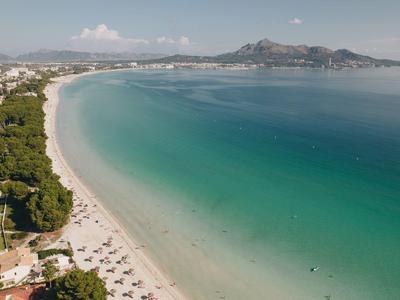 Larga playa de arena con agua turquesa y complejo hotelero en la costa.
