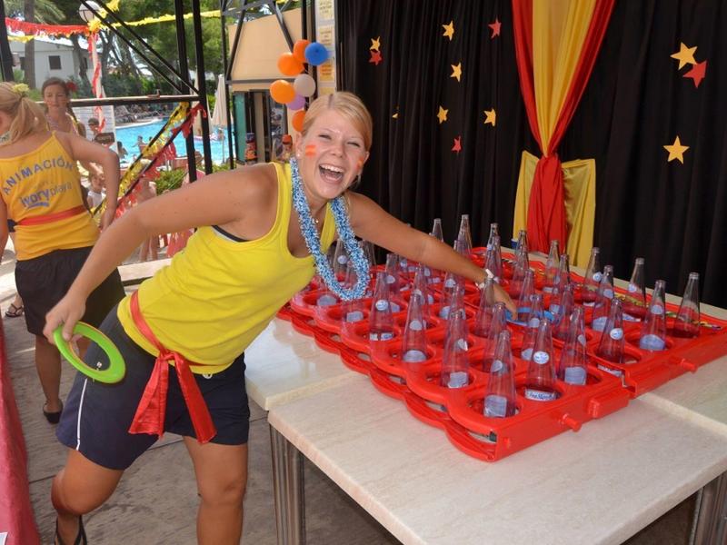 Niño feliz en un puesto de bebidas en un parque de diversiones con fondo colorido.