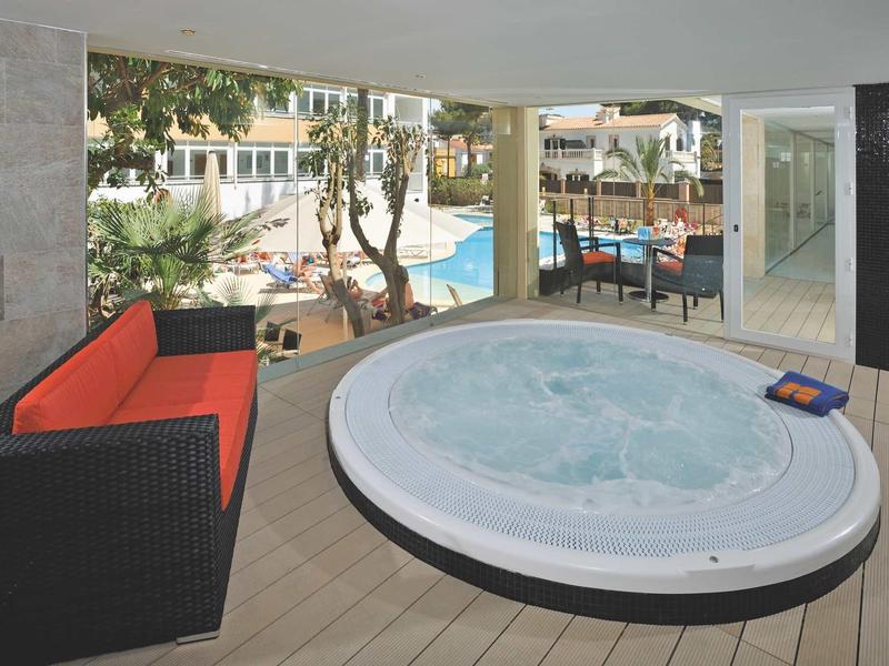 Widok na jacuzzi z miejscem do siedzenia i basenem w tle w hotelu.