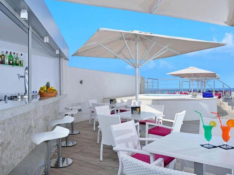 Nowoczesny teren zewnętrzny z barem, białymi krzesłami i parasolami w słoneczny dzień nad morzem
