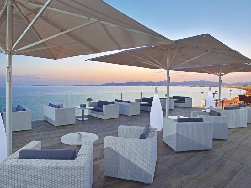 Nowoczesny taras na dachu z białymi meblami wypoczynkowymi i dużymi parasolami o zachodzie słońca