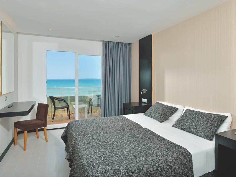 Nowoczesny pokój hotelowy z łóżkiem podwójnym i widokiem na morze przez duże okna.