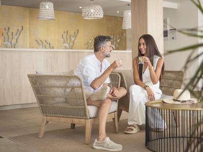Zwei Personen sitzen in einem modernen Hotel-Loungebereich und unterhalten sich bei Getränken.