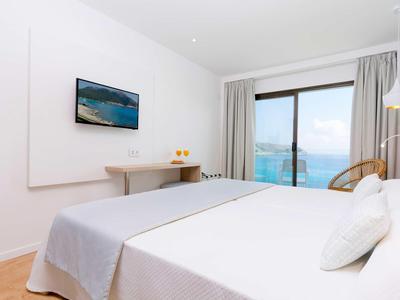 Camera d'hotel moderna con letto matrimoniale, ampia finestra panoramica e vista sul mare.