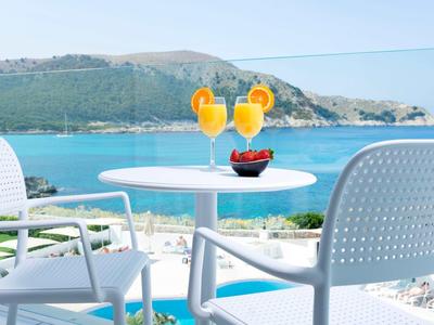 Terrazza con vista mare, tavolo tondo blu con due cocktail e frutti rossi.