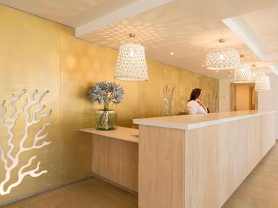 Reception elegante con parete dorata, illuminazione soffusa e decorazioni floreali.