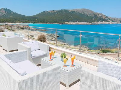 Nowoczesne białe meble lounge na tarasie z widokiem na morze i góry w tle.