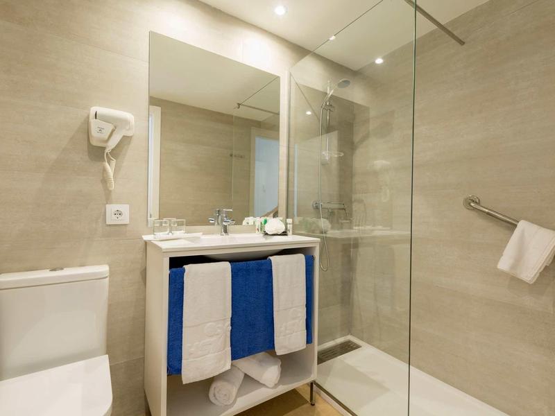 Bagno moderno con wc, doccia a filo pavimento e mobile lavabo blu.
