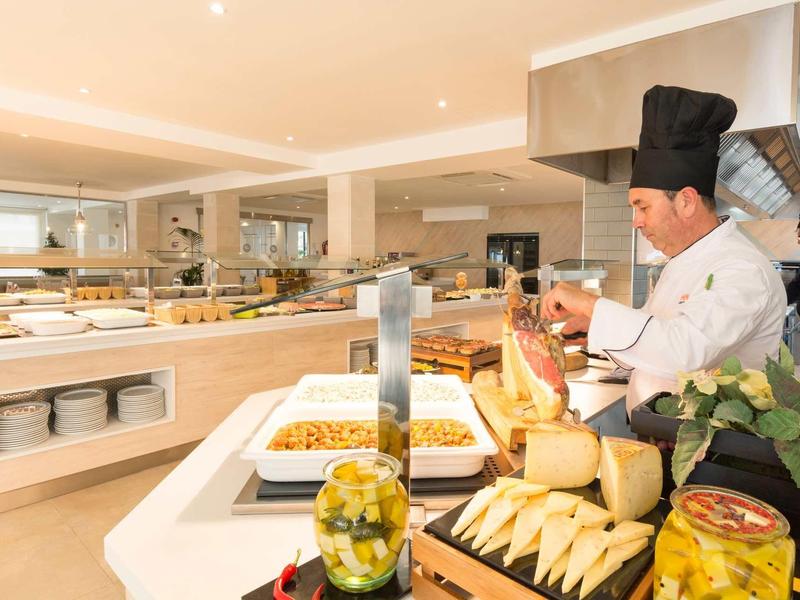 Chef che prepara piatti in un buffet luminoso e moderno dell'hotel.