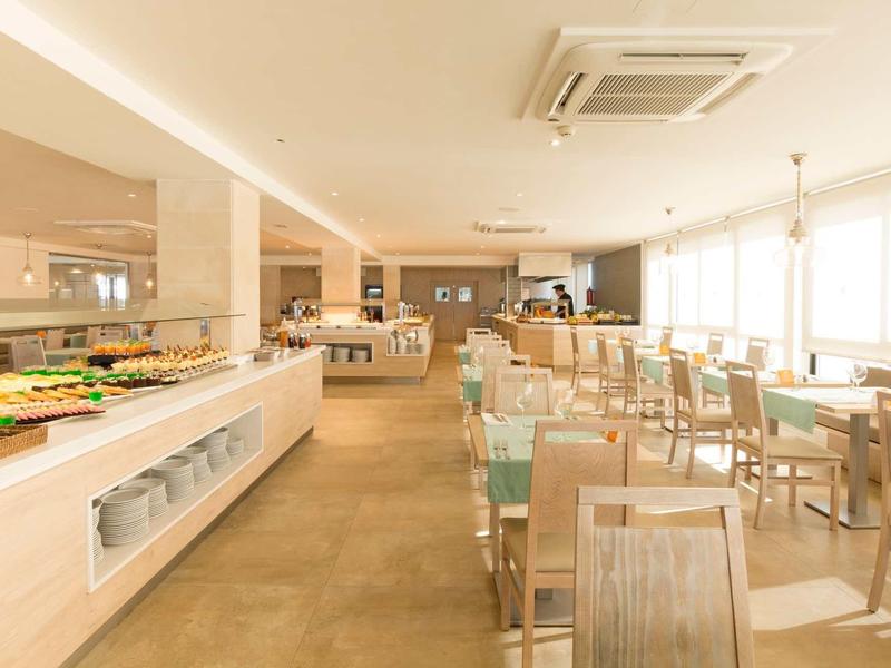 Sala da pranzo luminosa con buffet e sedie in legno chiaro.