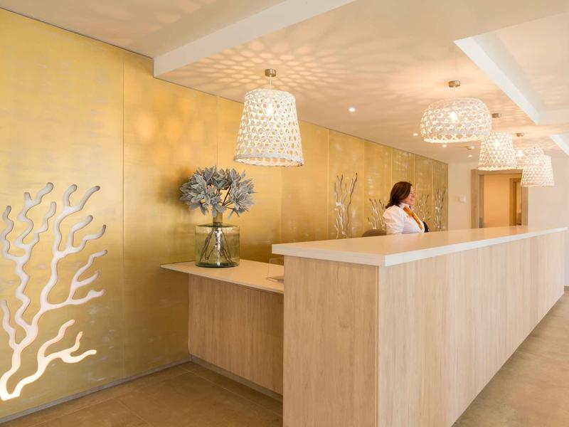 Reception elegante con parete dorata, illuminazione soffusa e decorazioni floreali.