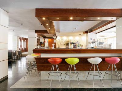 Moderne bar met kleurrijke krukken, houten toonbank en stijlvolle inrichting in lichte sfeer.