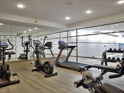 Moderne fitnessruimte met loopband, spinningfiets, halters en grote spiegels.