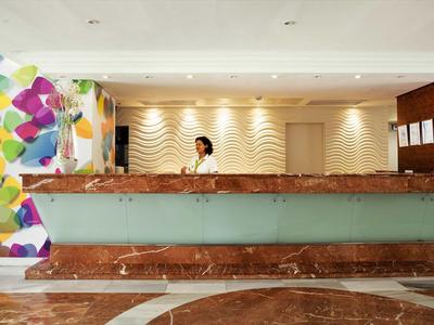 Recepcja w nowoczesnym hotelu z kolorową dekoracją ściany i marmurową podłogą.