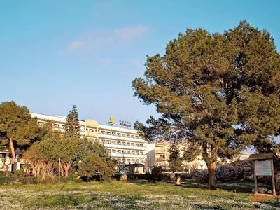 Budynki hotelowe z wieloma piętrami otoczone drzewami i trawiastym terenem pod czystym niebem