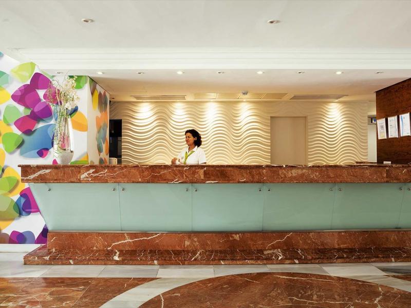 Recepcja w nowoczesnym hotelu z kolorową dekoracją ściany i marmurową podłogą.