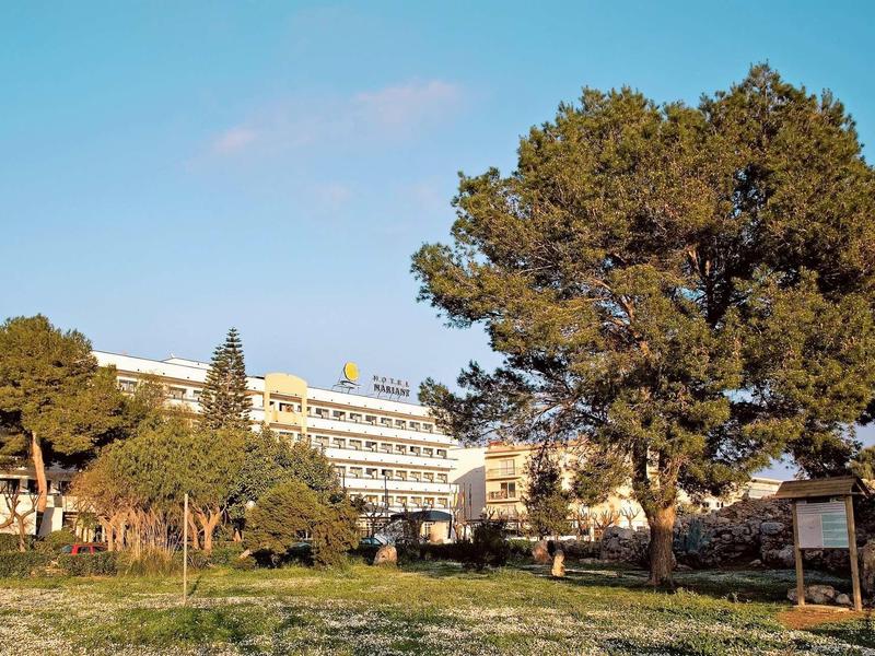 Budynki hotelowe z wieloma piętrami otoczone drzewami i trawiastym terenem pod czystym niebem