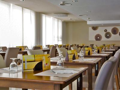 Moderner Speisesaal mit hellen Tischen, Stühlen und großen Fenstern