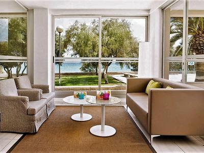 Gezellige zithoek met uitzicht op water en bomen door grote ramen.