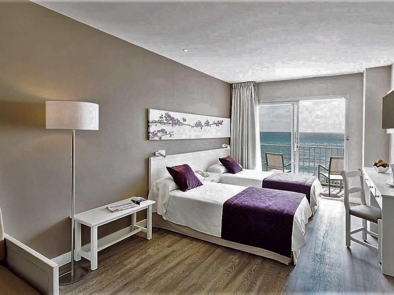 Nowoczesny pokój hotelowy z widokiem na morze i podwójnym łóżkiem.