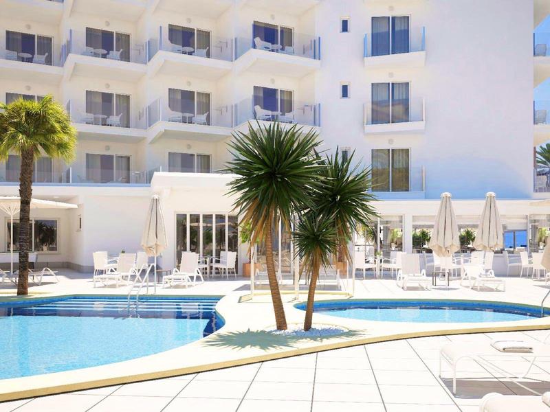 Sunny hotel pool area with palm trees, white lounge chairs, and balconies on the building.