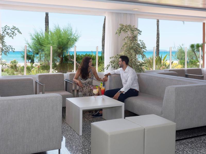 Couple enjoying drinks on a spacious outdoor patio with ocean view and modern seating.