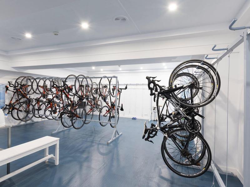 Indoor bike storage with multiple bicycles mounted on racks in a clean, well-lit room.