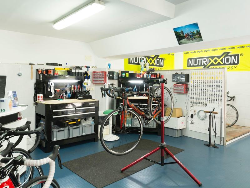 Bike repair workshop with tools, bikes, and a bike mounted on a repair stand indoors.