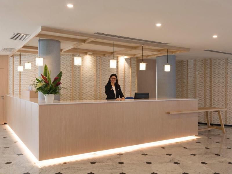 Modern hotel reception area with a sleek, illuminated desk and a receptionist on the phone.