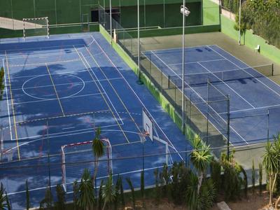 Zwei Tennis- und Paddleplätze in einem eingezäunten Bereich mit umliegendem Grün.