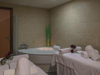 Ein Whirlpool in einer ruhigen Spa-Ecke mit weißen Handtüchern, Rosen und sanfter Beleuchtung.