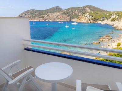 Balkon mit Tisch und Stühlen mit Blick auf das Meer und Hügel im Hintergrund.