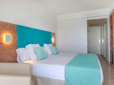 Modernes Hotelzimmer mit Doppelbett, türkisem Akzent und minimalistischer Einrichtung.