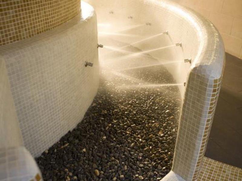 Geschwungene Treppe mit kleinen weißen Fliesen und dunklem Kies am Boden einer modernen Innenraumgestaltung.