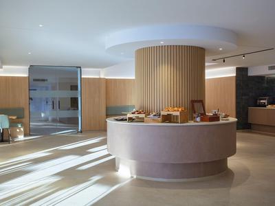 Hotel moderno con un banco reception rotondo e accenti in legno in una stanza luminosa.