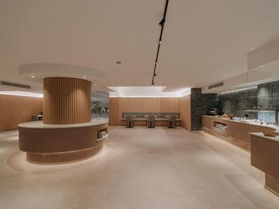 Großer, moderner Hotel-Lobbybereich mit warmen Holzakzenten und minimalistischer Einrichtung.
