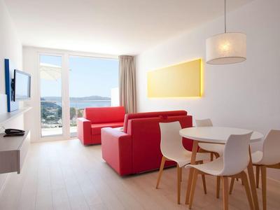 Bright living room with red armchairs, dining table, and view of water and hills.