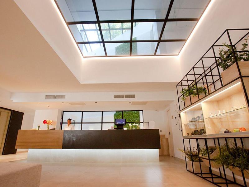 Modern hotel lobby with bright interior, reception desk, and large skylights.