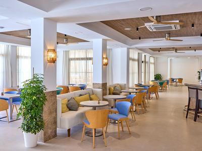 Heller, moderner Speiseraum mit blauen und orangenen Stühlen, Sofas und Pflanze in Weißtopf.
