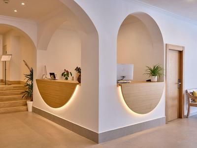 Heller Empfangsbereich mit zwei runden Tresen und Bogenfenstern in cremeweißer Wandgestaltung.