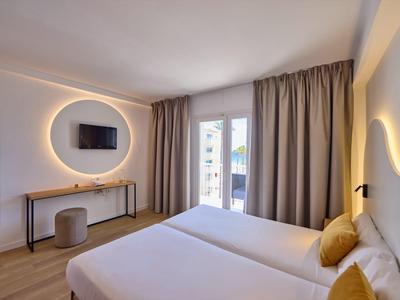 Helles Schlafzimmer mit zwei Betten, grauen Vorhängen, runder beleuchteter Spiegel und stilvollem Lichtdesign.