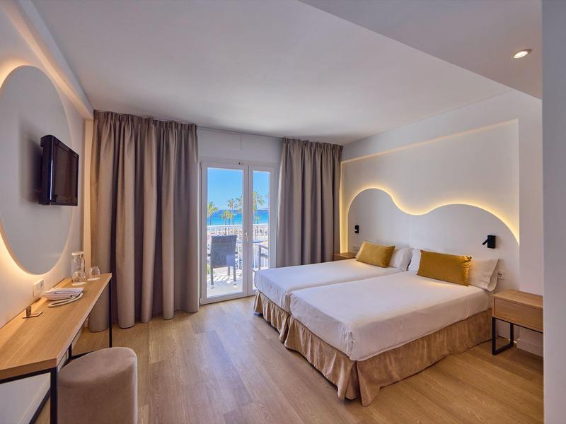 Camera d'hotel moderna con letto matrimoniale, luce soffusa e balcone con vista mare.