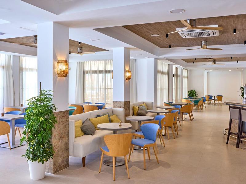 Bar dell'hotel moderna con aree salotto accoglienti, sedie colorate e luce naturale.